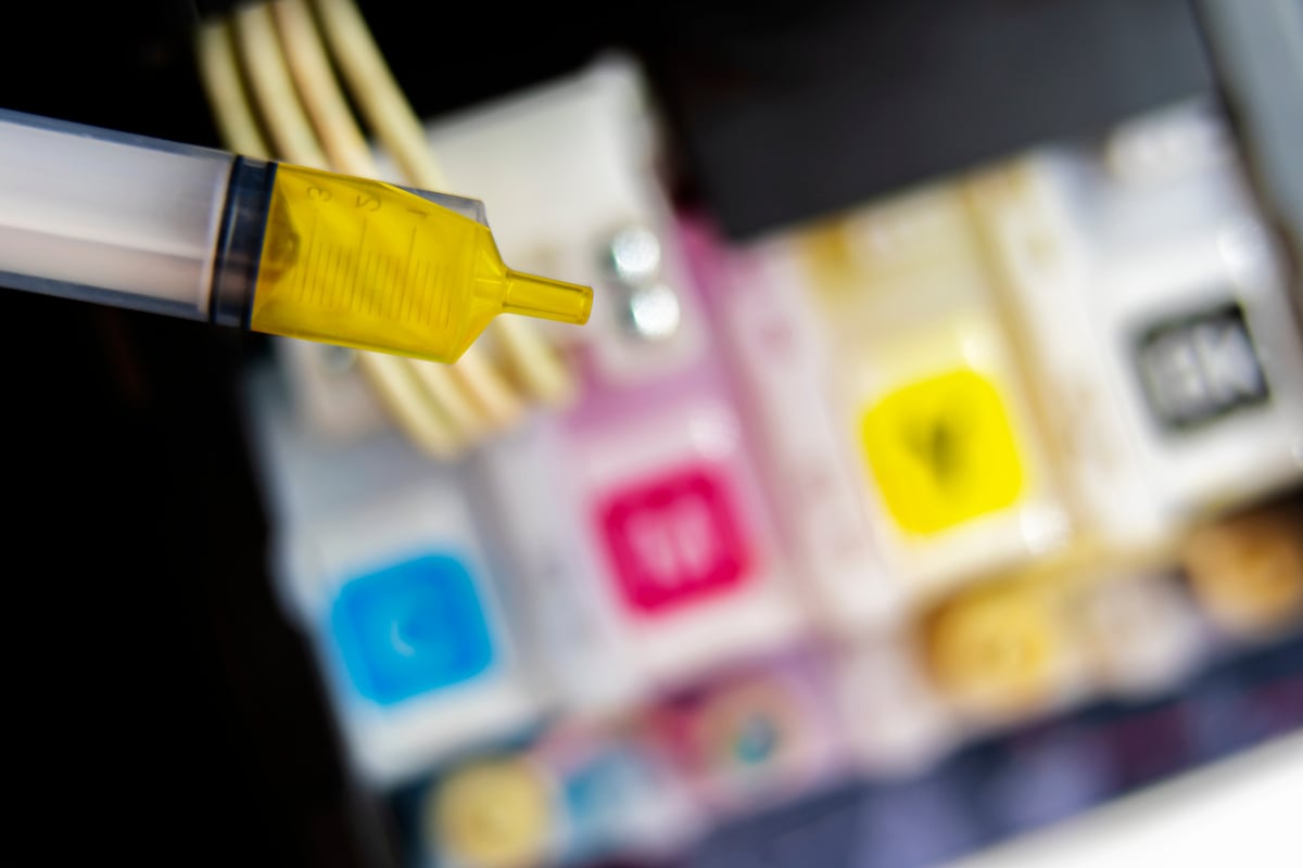 Closeup Refilling Ink into a Yellow Ink Tank Printer at Office