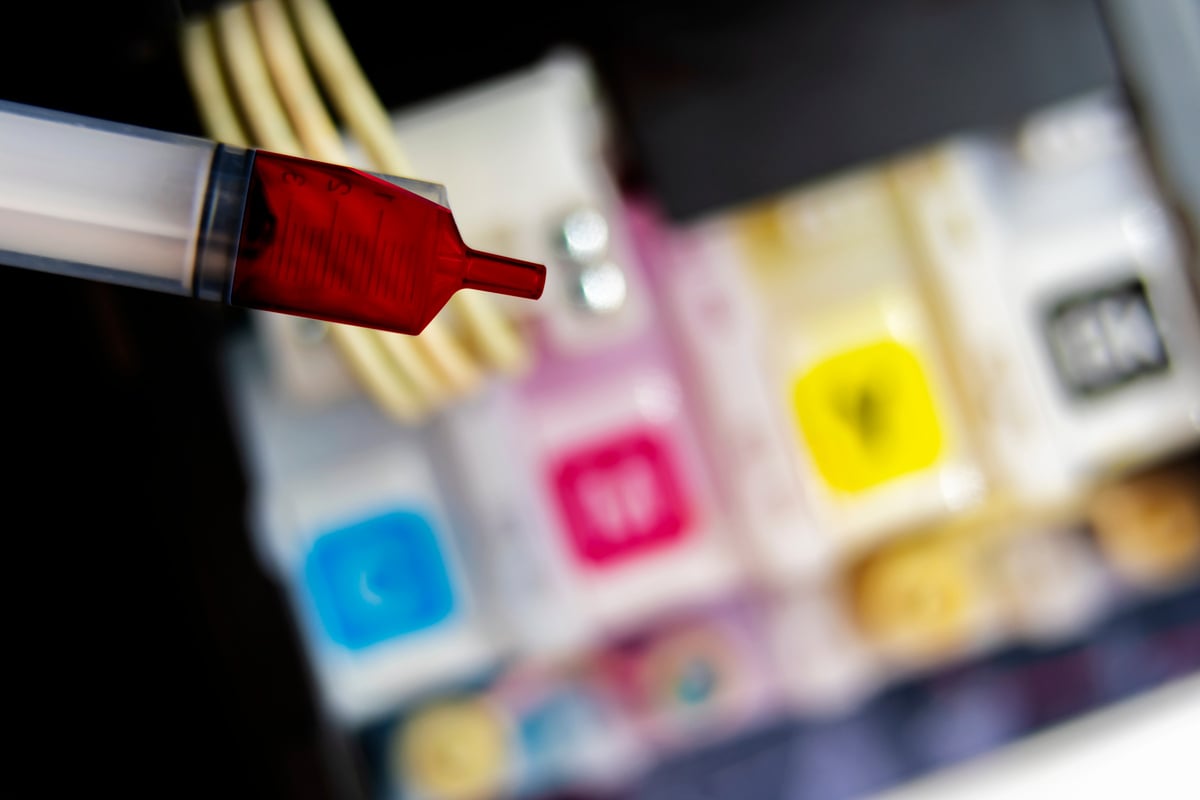 Closeup Refilling Ink into a Red Ink Tank Printer at Office