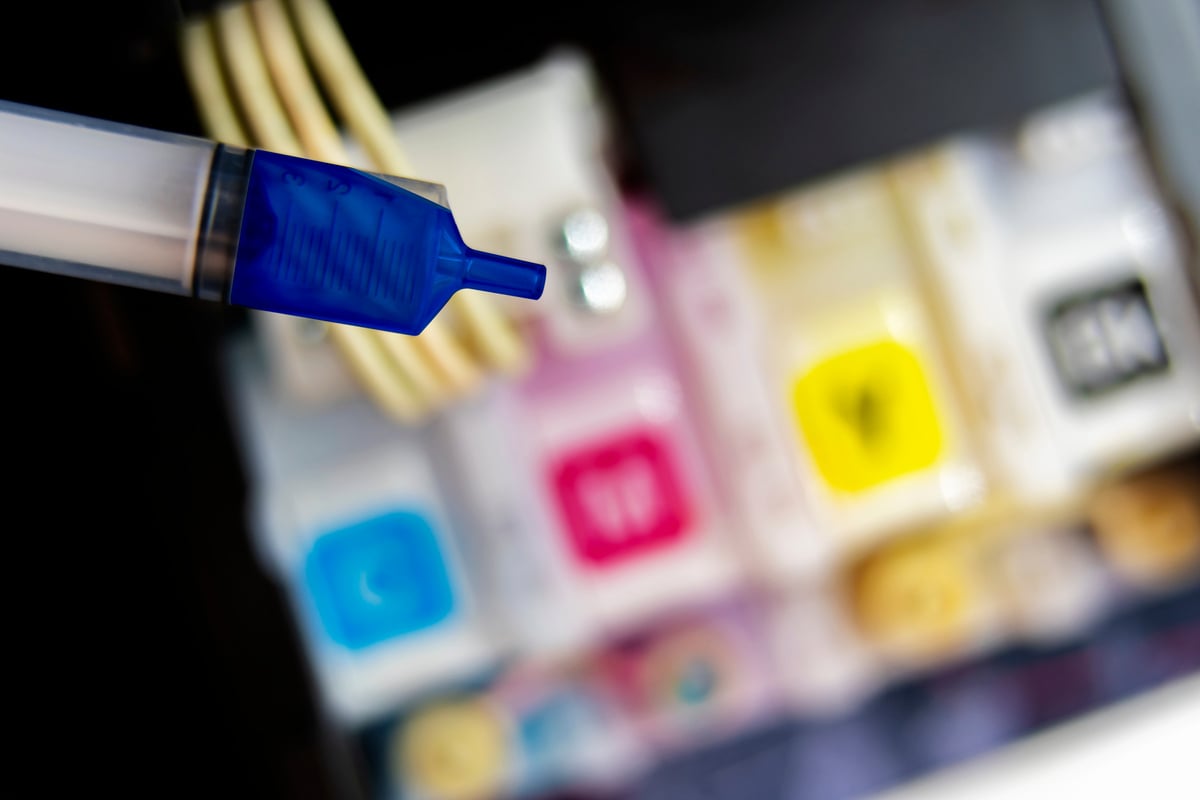 Closeup Refilling Ink into a Blue Ink Tank Printer at Office